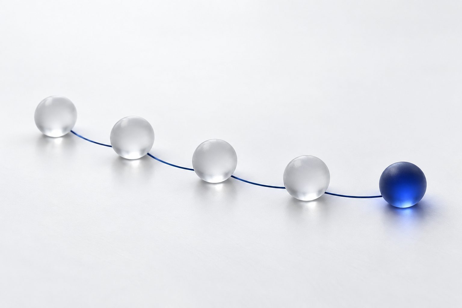Five frosted glass spheres in an arc on a white surface, joined by thin lines of navy light
